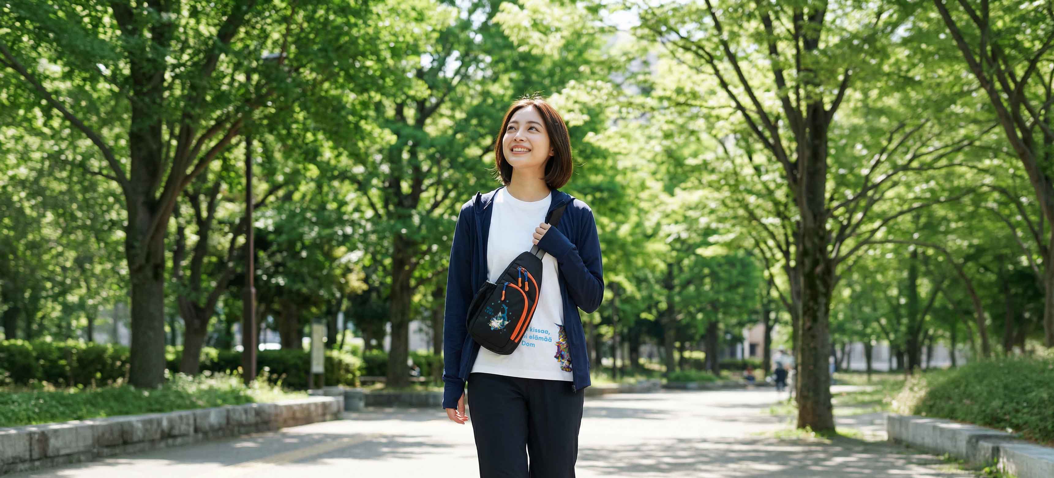 木漏れ日の中を歩く女性・TOMOKO KATOU MOI柄ブラックのNEKONI SLING