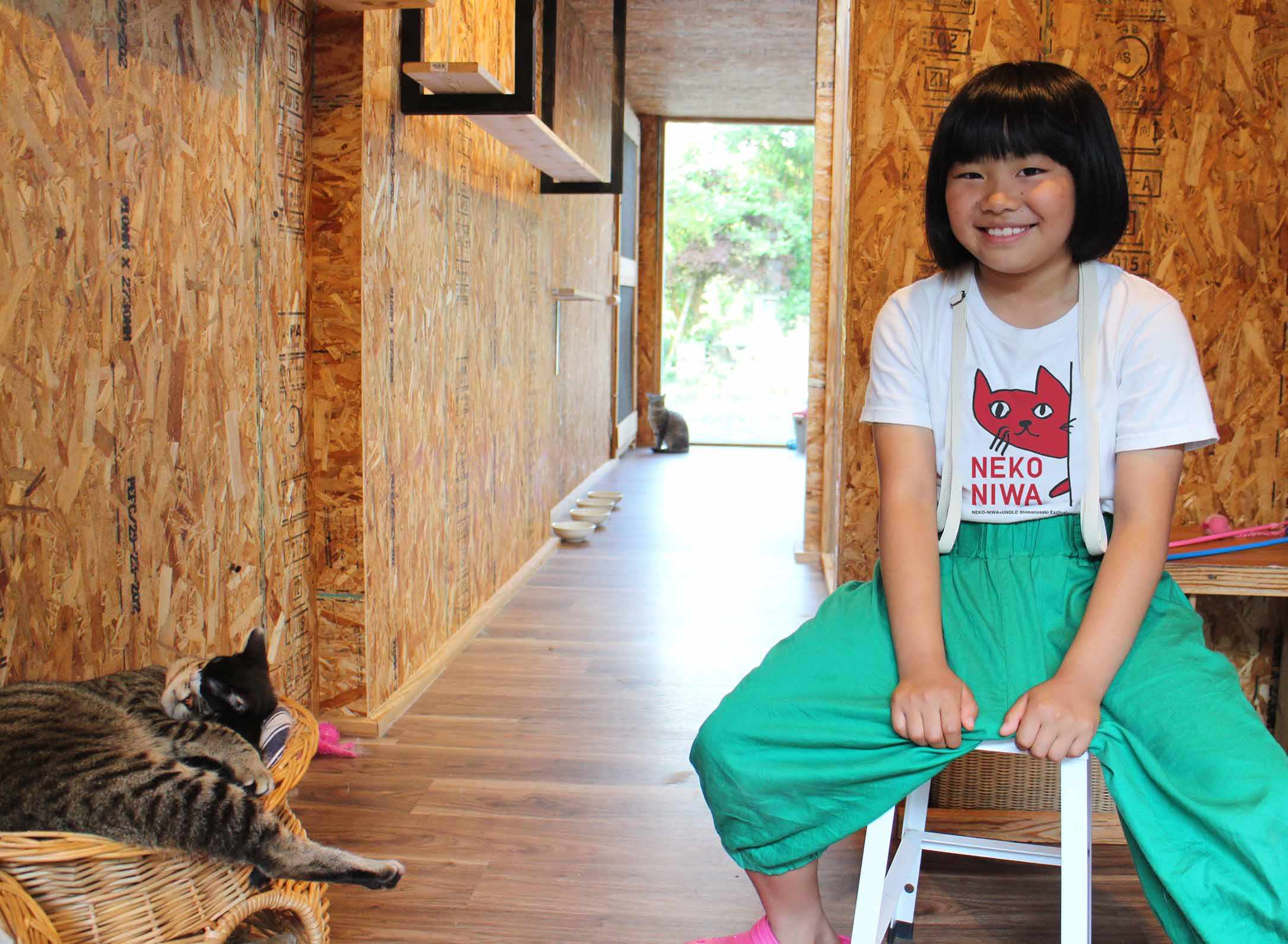 NEKONIWAのTシャツを着る少女と猫庭の猫たち